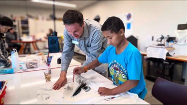 Patrick-helping-a-boy-put-a-design-on-a-t-shirt.jpeg